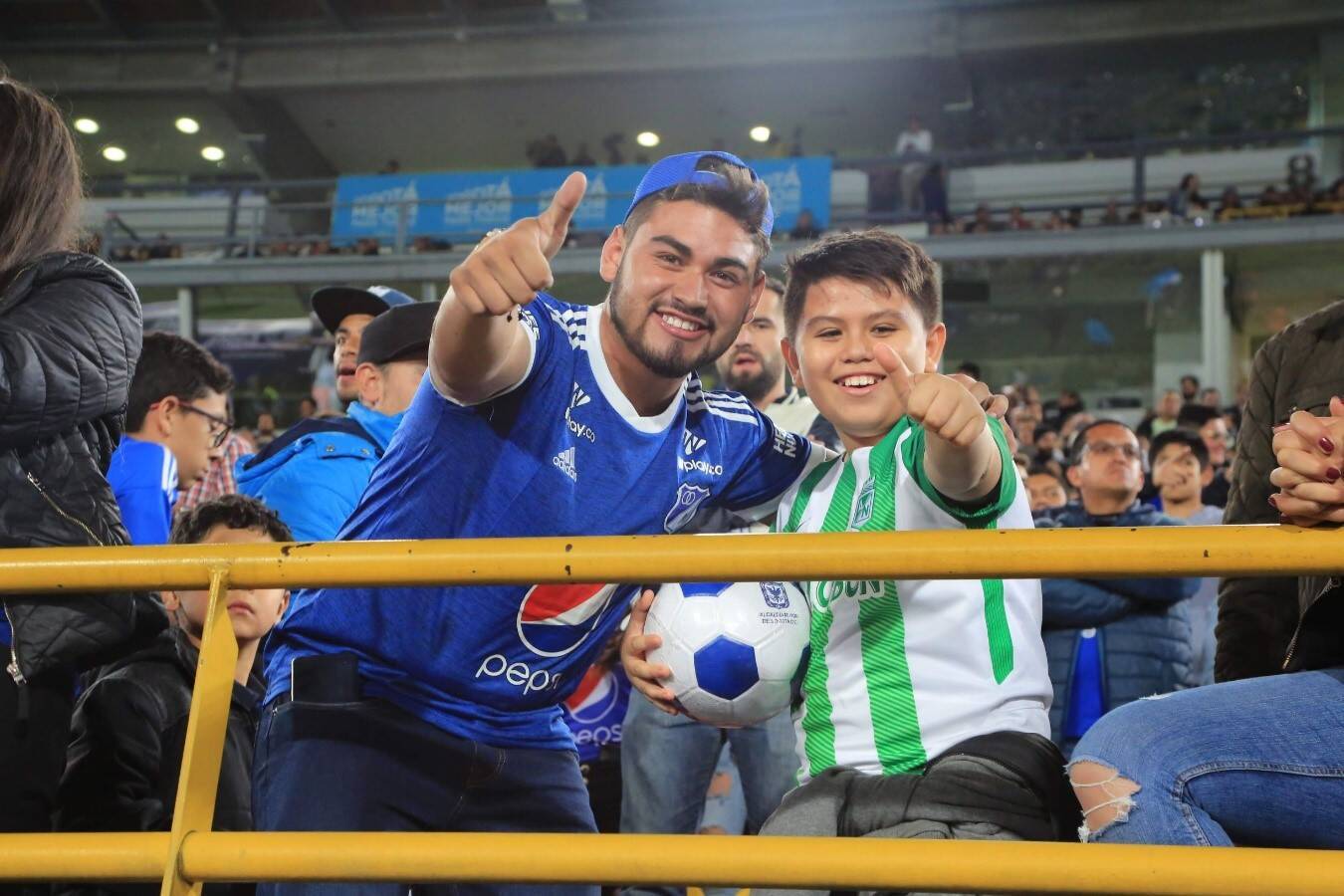 Hombre y niño hinchas de equipos opuestos sonríen