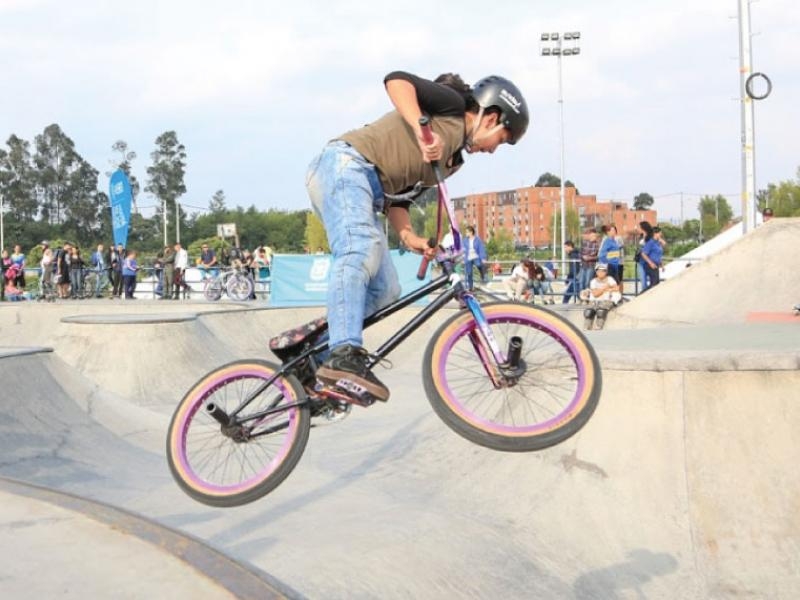 Mujer monta bicicleta en pista de skate